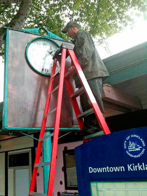 A city employee stands on a ladder to disassemble the ferry clock in downtown Kirkland in 2011.