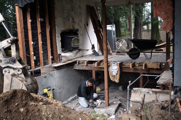 Marco Santos of Angel's Concrete works to prepare the foundation of the Ladson home for reconstruction. A Kirkland Police car crashed into the home last December