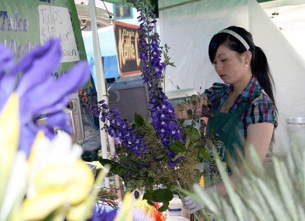 Moua Vang of Snohomish-based Moua Garden prepares a bouquet of flowers during the opening day of the Friday Market at Juanita Beach.