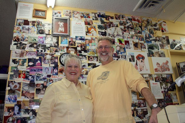 Dooley's Dog House owners Chuck and Marti Bartlett stand in front of a wall covered in photos of dogs and cats adopted during past 12 years through their store.