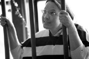 Sharon VonClasen poses behind a plastic-bars set up as a Muscular Dystrophy Association volunteer takes her picture after she was “arrested” and “served time” at a mock jail at the Wilde Rover last Thursday. Each participant made phone calls to raise money for their “bail.” The event raised over $26