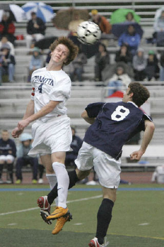 Juanita’s Tyler Bjork (No. 4) beats Olympia’s Jasper Knox (No. 8) to a header during a 4A state tournament game at Juanita High School May 13.