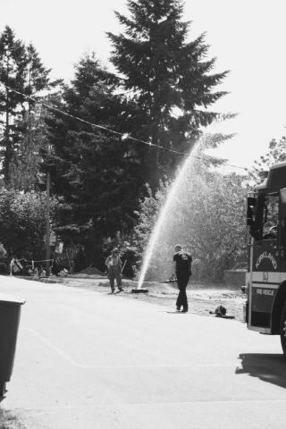 Kirkland Fire Department Lt. Margo Freeman and firefighter Moe Kelsey prepare to reroute water shooting from a broken water pipe between 18th and 20th Avenue West on 9th Street on May 27. Witnesses said a dump truck
