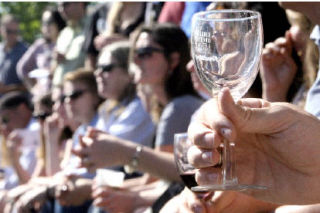 A festival-goer holds up an empty wine glass as a crowd waits for the start of a cooking competition in the wine garden area at the Kirkland Uncorked Festival at Marina Park on July 19. Organizers estimated over 20