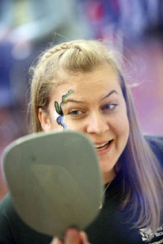 Desiree Conway reacts as she sees her face painting in a mirror during the International Extravaganza at Lake Washington Technical College on July 30. The free event featured an international talent show and an international food bazaar.