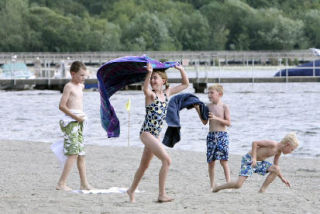 Rosalind Farrell looks back at her towel as the wind whips it behind her while playing on the beach with Ben Nussbaum