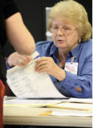 Poll worker Jeanette Merki gets a ballot ready for a voter during the 2008 Primary Election at a polling place located inside Christ Church of Kirkland on Tuesday