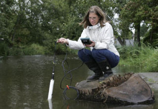 The Department of Ecology checked Juanita Creek and beach Aug. 27 to determine the source of fecal coliform bacteria. Julie Gaertner drops a component of Hydrolab into Juanita Creek for a quick calibration.