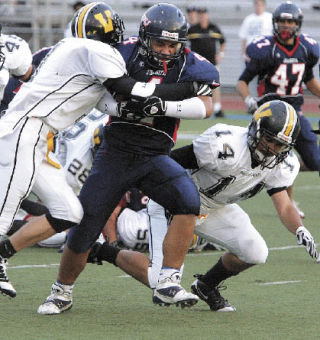 Juanita’s Jerimiah Laufasa (No. 4) holds on to the ball as the Inglemoor defense drags him down during first quarter action of the game at Juanita High School on Friday