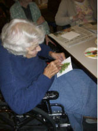 Mildred Bruns with Áegis of Kirkland puts her finishing touches on a painting that will be used for the Wrap A Senior In Love Campaign.