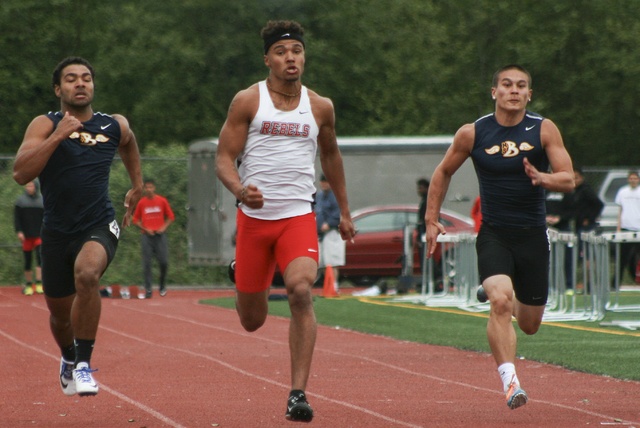 Juanita High senior Makiah Gilmer is framed by a pair of Bellevue runners while competing in the 100 meter dash on Thursday