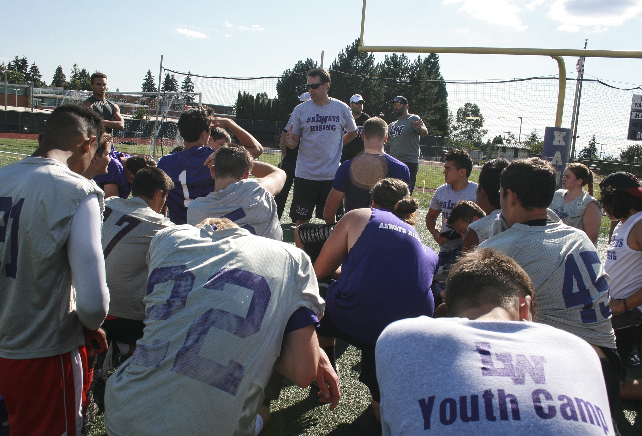 Players gather around coach AJ Parnell following a summer workout session at Lake Washington High School on Wednesday