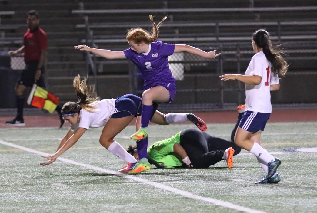 Lake Washington freshman Jen Estes (2) and Juanita sophomore Michela Flock-Yakes tumble over Juanita goalkeeper Nataya Bauer during the first half on Thursday