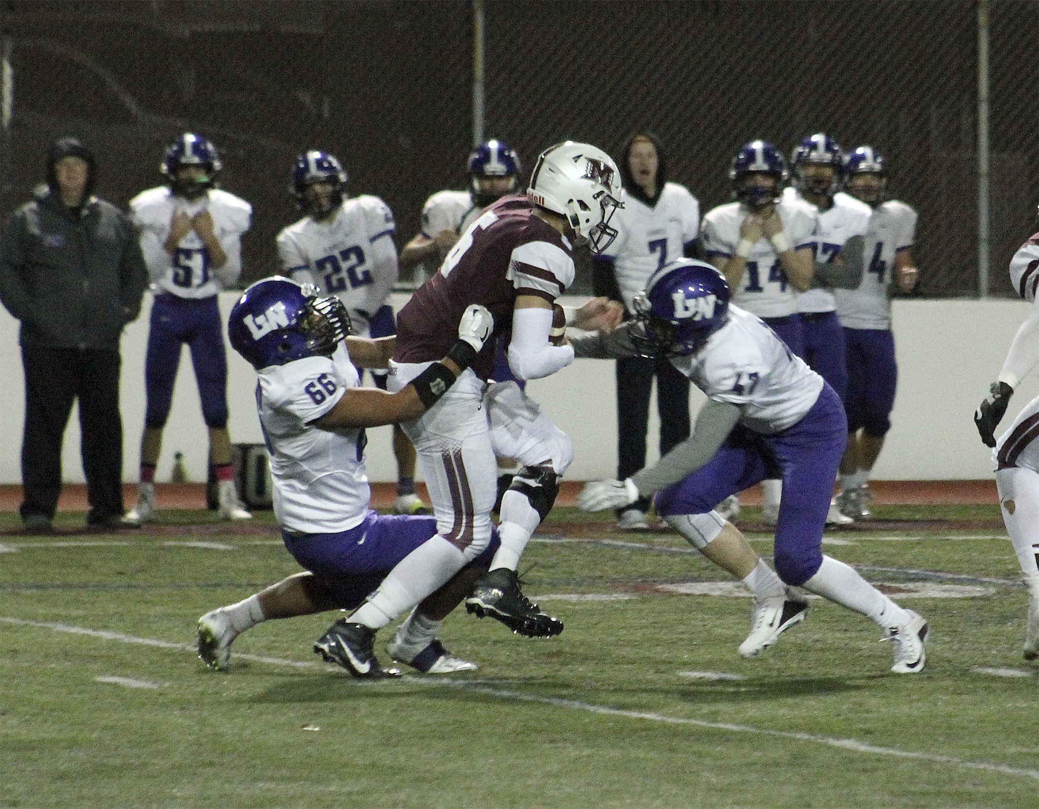 Lake Washington’s Chris Chaplin (66) and Conor Quigley (47) wrap up Mercer Island quarterback Nikhil Nayar during the second half of the Kangs’ KingCo matchup against the Islanders Friday night at Mercer Island High School. Lake Washington beat Mercer Island 34-13. Joe Livarchik/Mercer Island Reporter.