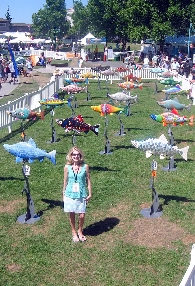 Kirkland resident Kathy Feek stands with the Fish Frolic sculptures during Kirkland Summerfest. Fish Frolic is just one of the many art events that Feek has put her heart into to benefit the Kirkland art scene.
