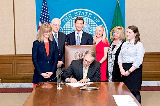 Rep. Patty Kuderer looks on as Governor Inslee signs HB 2425.