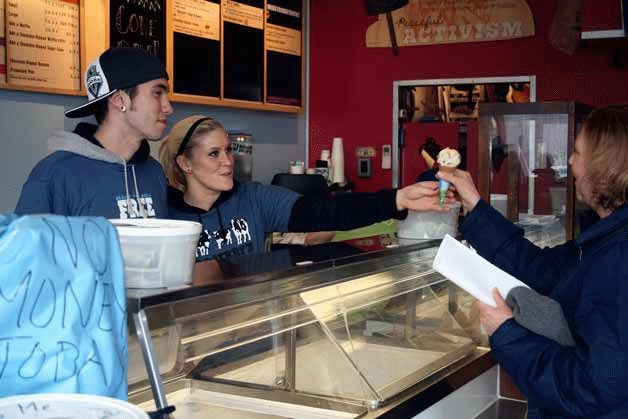 Kirkland Ben & Jerry's employees hand an ice cream cone to a customer during the company's annual free cone day in 2012.