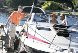 Dockmaster Chris Schei hands out information about an upcoming city event to Kim E. Grant and Gene Tremelling at the Kirkland Marina on July 11.
