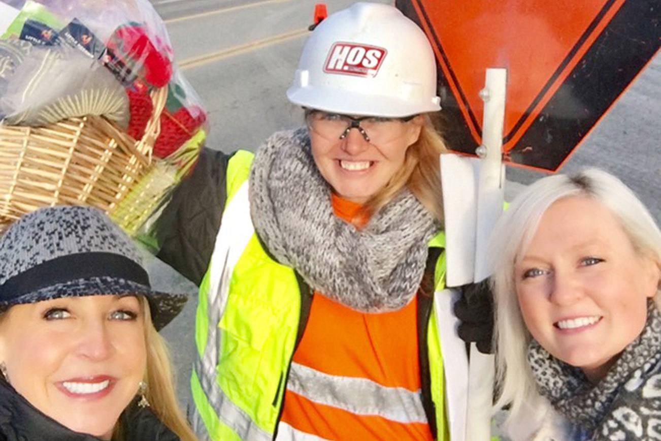 Barbie Collins Young (left) and Jody Anderson (right) present Felicia Porter with a holiday gift basket outside of the Kirkland Urban construction site, where Porter works as a flagger. The gift basket is filled with items from appreciative Kirkland residents. Contributed photo