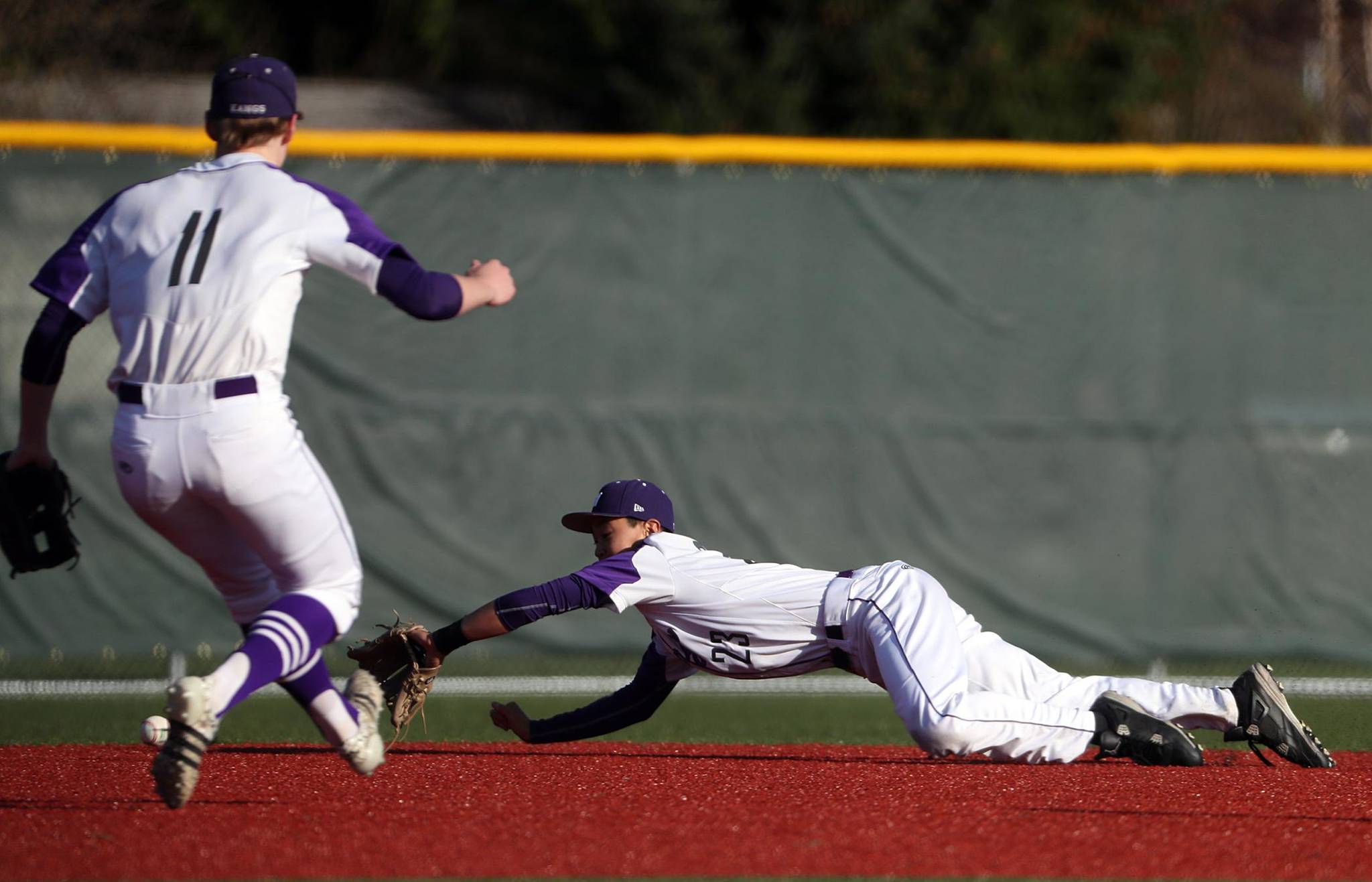 Lake Washington shortstop Travis Lee dives for the ball while Alex Lyon looks on during Wednesday’s game. Corky Trewin photo