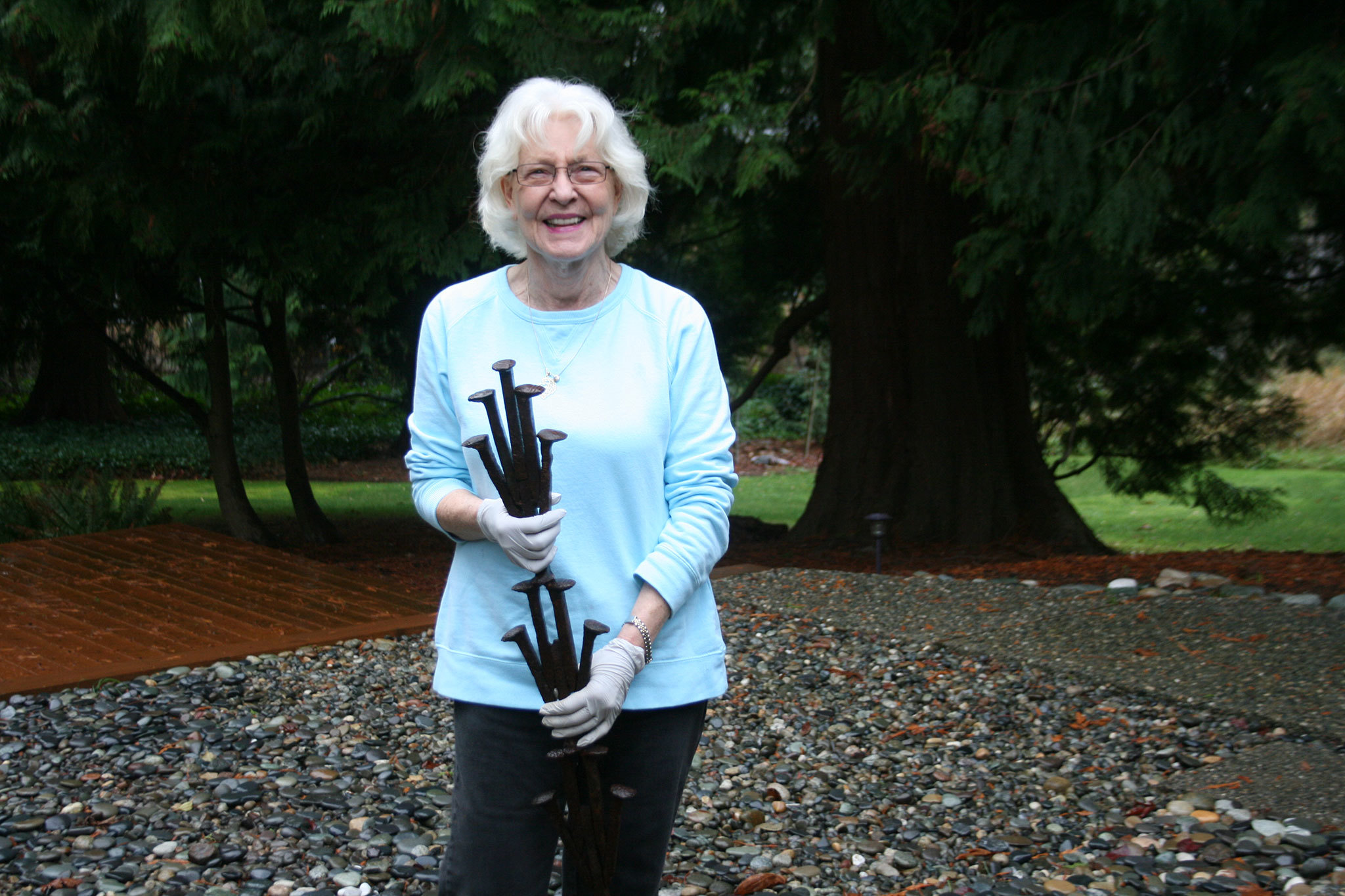 Merrily Dicks holds a sample of “The Spikes” sculpture that is displayed in her Kirkland backyard. One of her assistants, Yancy McCoy, helped create this piece. The full sculpture has been installed on the Cross Kirkland Corridor. CATHERINE KRUMMEY / Kirkland Reporter