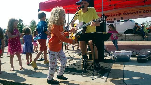 Kids dance alongside a performer at a previous Kirkland Summer Concerts event. Reporter file photo