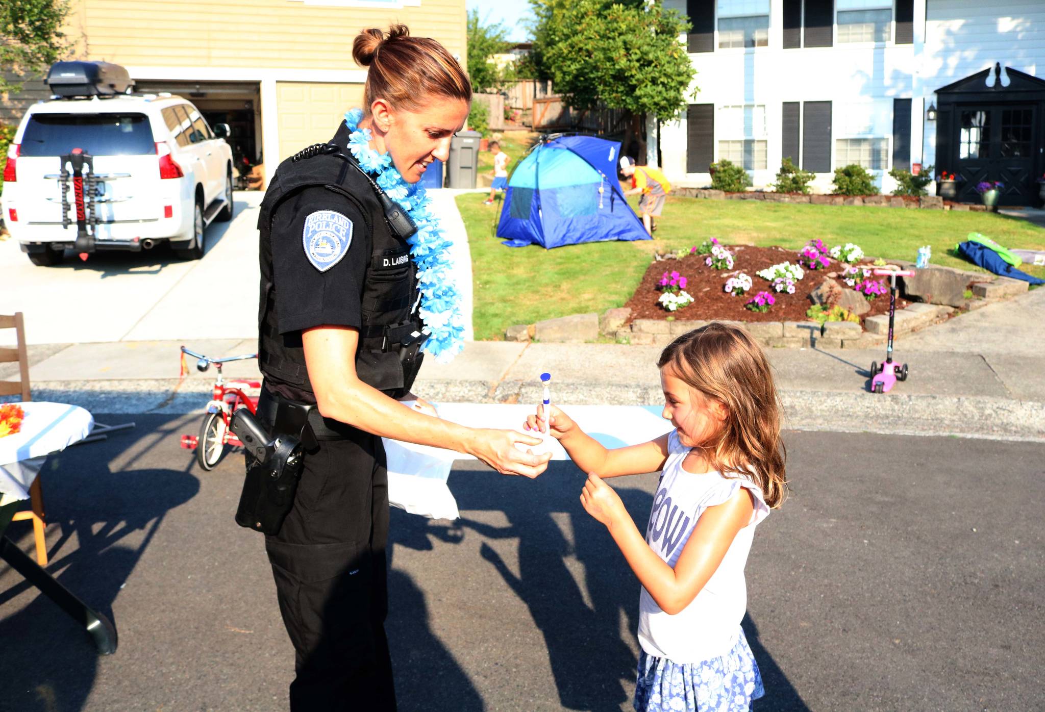 Neighborhood Resource Officer Deana Lansing hands Isabella Adkins, 6, a pen during a community cookout in the 13600 block of 116th Avenue Northeast in Kirkland on National Night Out Tuesday. Megan Campbell/staff photo