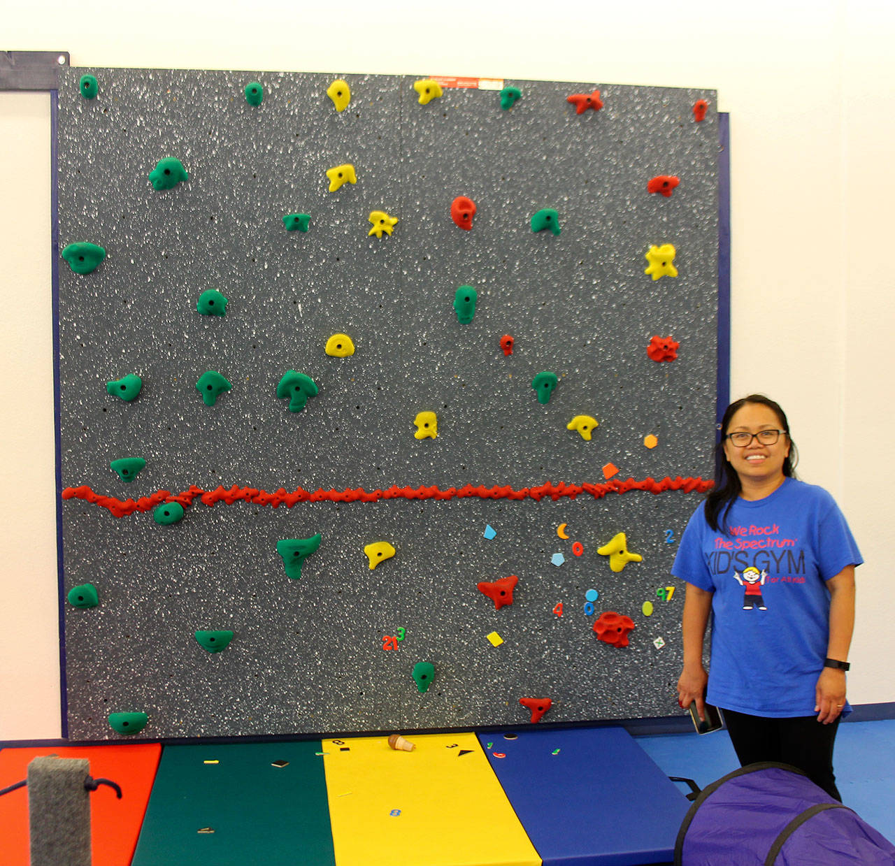 Co-owner of the Bellevue We Rock the Spectrum, Shirley Sarmiento-Blaha, stands in front of the gym’s rock wall. Raechel Dawson/staff photo