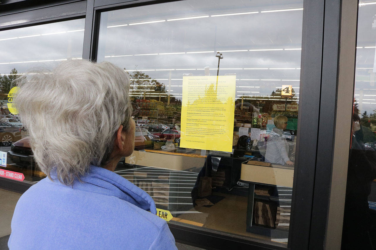 Kirkland resident Helge Nason reads the notice Bridle Trails Red Apple store owner Lori Croshaw posted about the store closure. Nason was sad to hear the store was closing its doors and spoke of the store’s “amazing” customer service. Megan Campbell/Kirkland Reporter