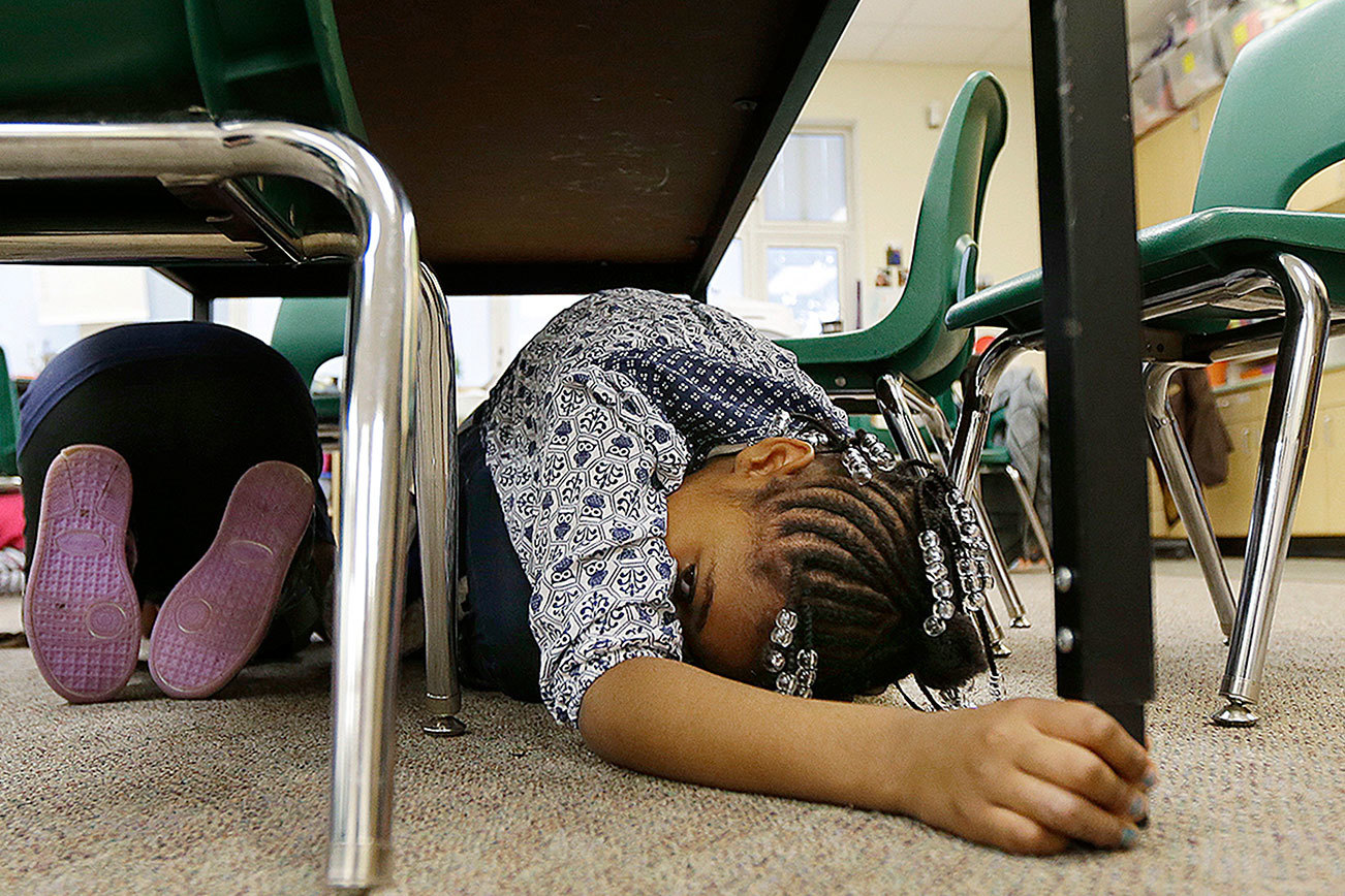 Sy’rai Beatty, 6, right, takes shelter under a table with other children in her first-grade class during an earthquake drill, Oct. 20, 2016, at Midland Elementary School in Tacoma, Wash. Schools, businesses, and community organizations conducted similar exercises across the state Thursday as part of the annual Great Washington ShakeOut earthquake and tsunami readiness program. (AP Photo/Ted S. Warren)