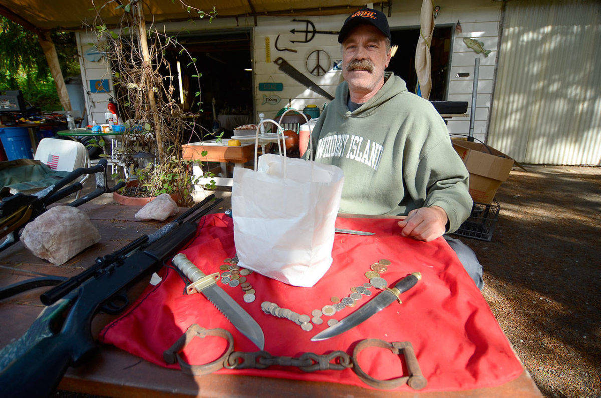 Clinton resident and picker John Norris poses for a photo with some of the items he found last year in a purchased storage unit. Inside the white sack are the remains of the skull. Photo by Justin Burnett