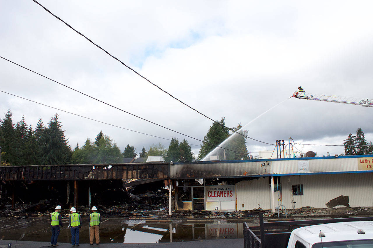 Kirkland firefighters and Puget Sound Energy staff examine the aftermath of a four-hour fire that destroyed the Rose Hill Village. Kailan Manandic/staff photo