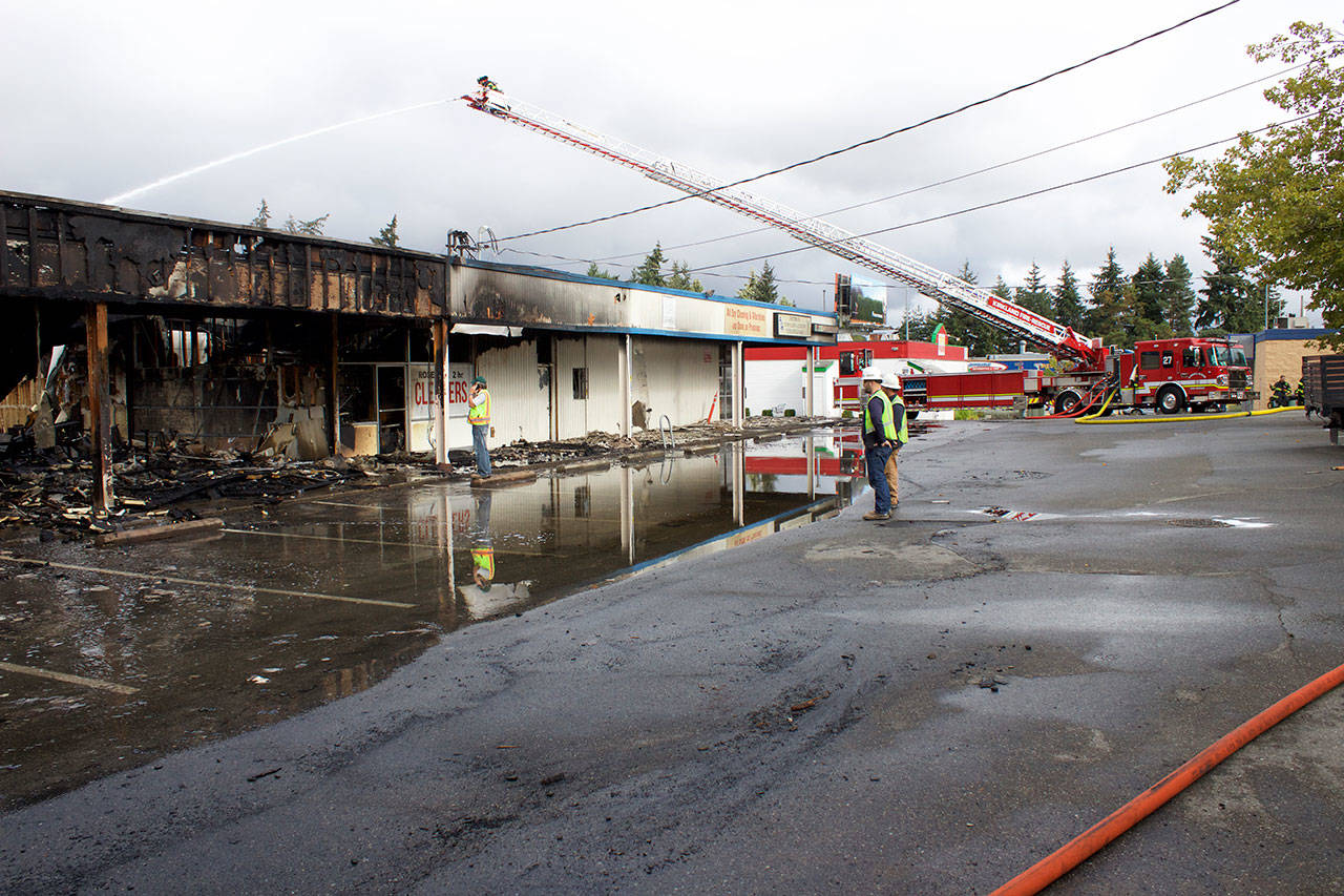 Kirkland firefighters water down hot spots after extinguishing the Rose Hill Village fire on Sept. 12. Kailan Manandic/staff photo