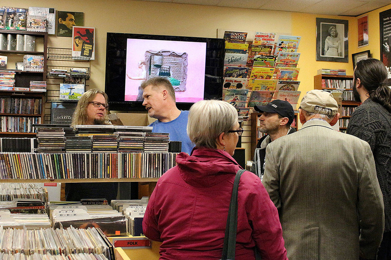 Greg McClellan (center) talks with friends at the release party for his 48 hour album, “Listen2Daze,” at Vortex Music & Movies in Kirkland. Madison Miller/staff photo.
