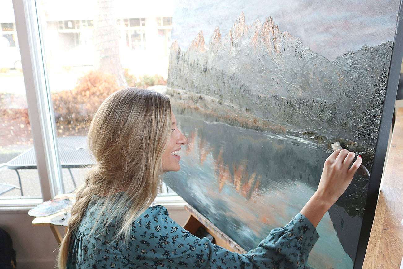 Elina Dmitruk uses Garrett King’s photo, “Grand Tetons” as a reference for her landscape painting at Zoka Coffee. She’s been painting this piece for about a month now. Stephanie Quiroz/staff photo