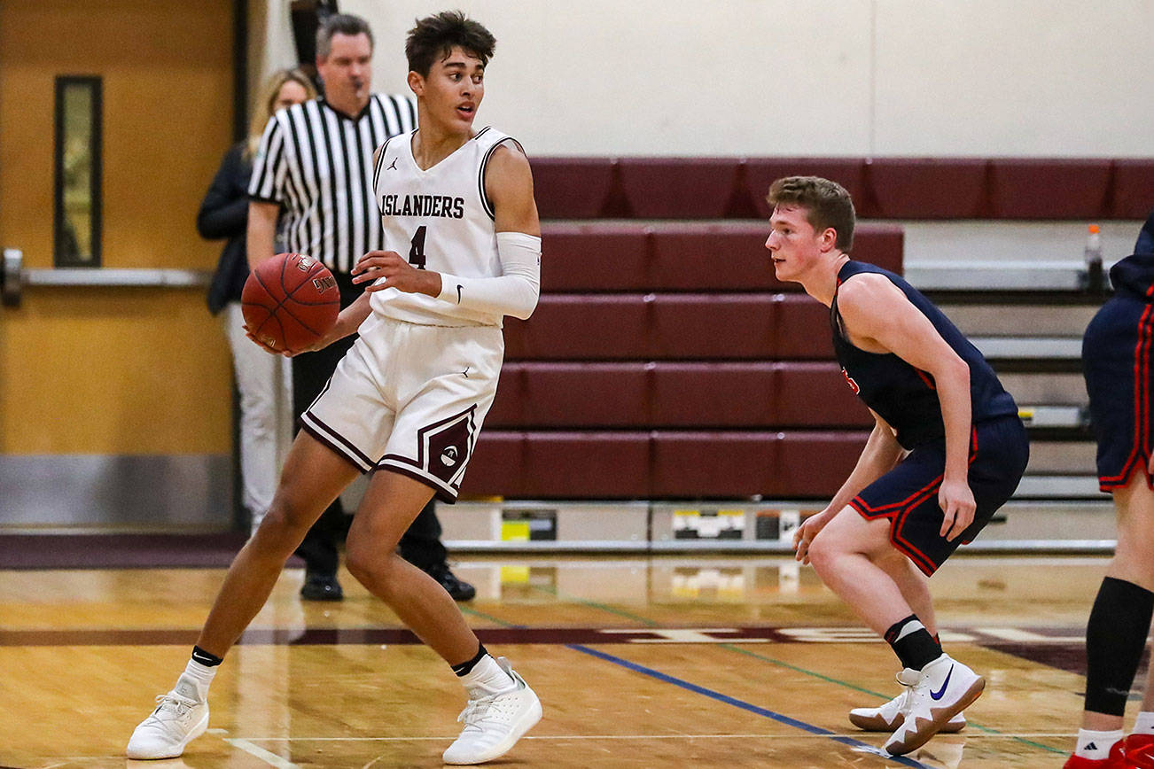 Mercer Island Islanders junior Adam Parker, left, looks for a teammate to pass to against the Juanita Rebels. Parker finished with a team-high 20 points against the Juanita Rebels on Dec. 11. The Islanders defeated the Rebels 56-49. Photo courtesy of Rick Edelman/Rick Edelman Photography