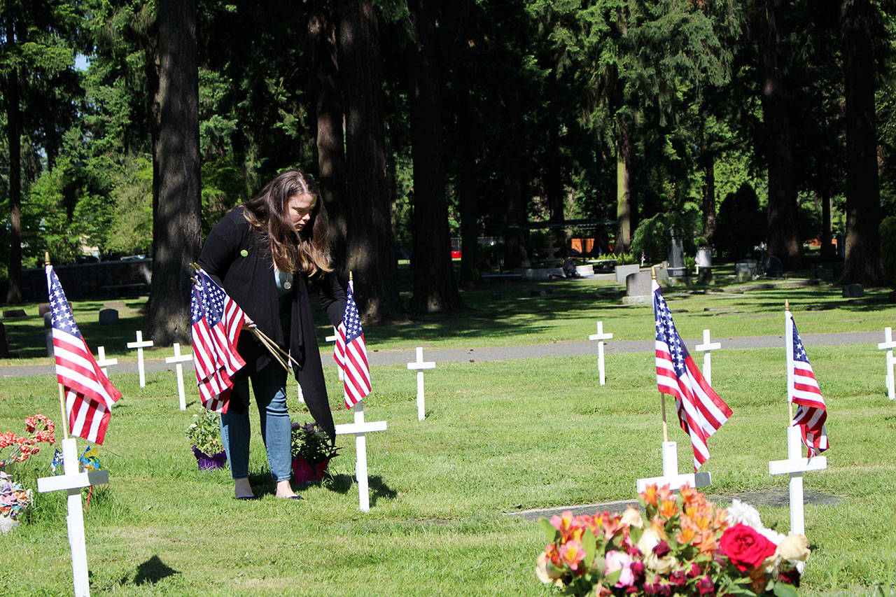 Kirkland City Council candidate Amy Falcone honors local veterans by planting U.S. flags among the white crosses commemorating their graves. Kailan Manandic / staff photo