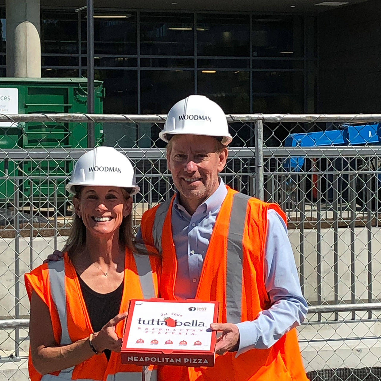 Suzy Monford, president of QFC (left), and Joe Fugere, owner of Tutta Bella (right) stand in front of the future Kirkland Urban location, holding a pizza box to commemorate the partnership. Photo courtesy of Tutta Bella Neapolitan Pizzeria