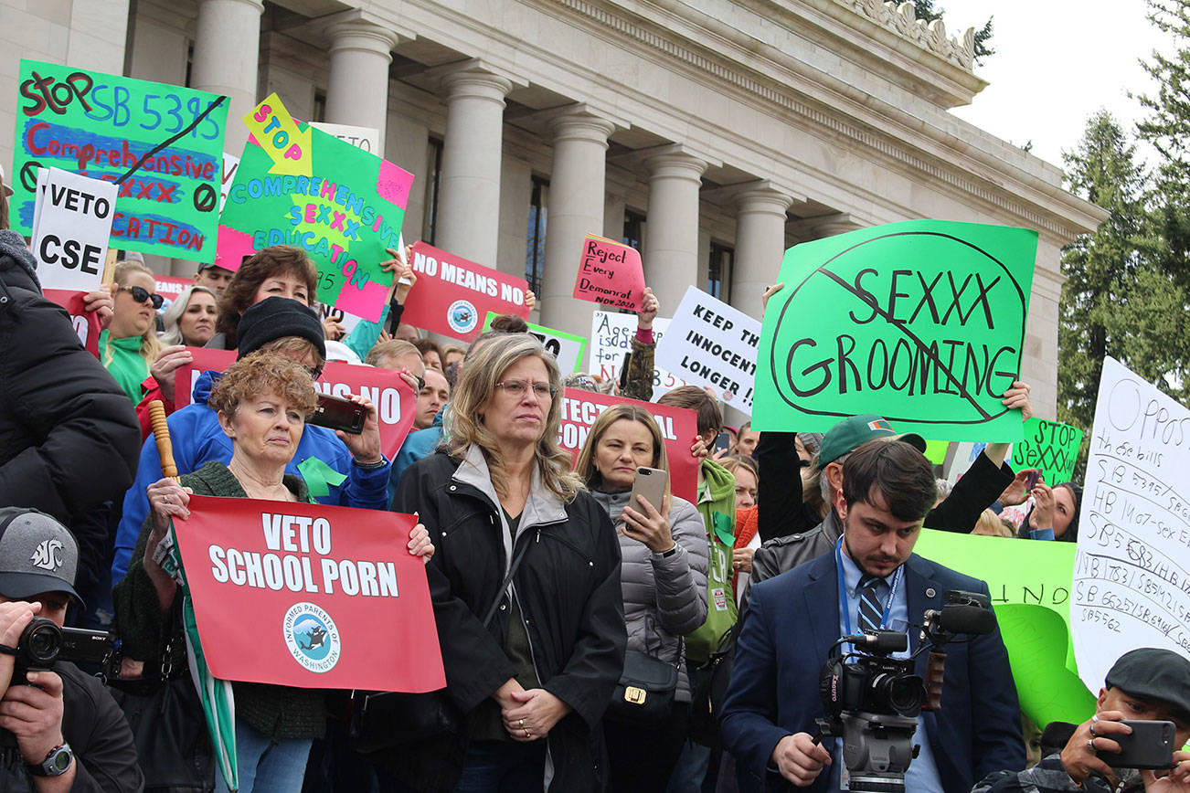 Protesters hold signs advocating for a veto on Senate Bill 5395. Photo by Cameron Sheppard, WNPA News Service