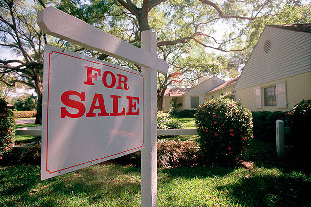 For sale sign hanging in front of house. File photo