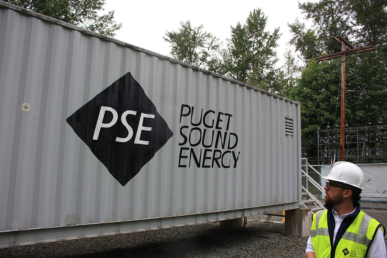 In this 2019 file photo, Puget Sound Energy product development manager John Dooley stands in front of one of four units at the Glacier Battery Storage Project in northwest Washington state. (Sound Publishing file photo)