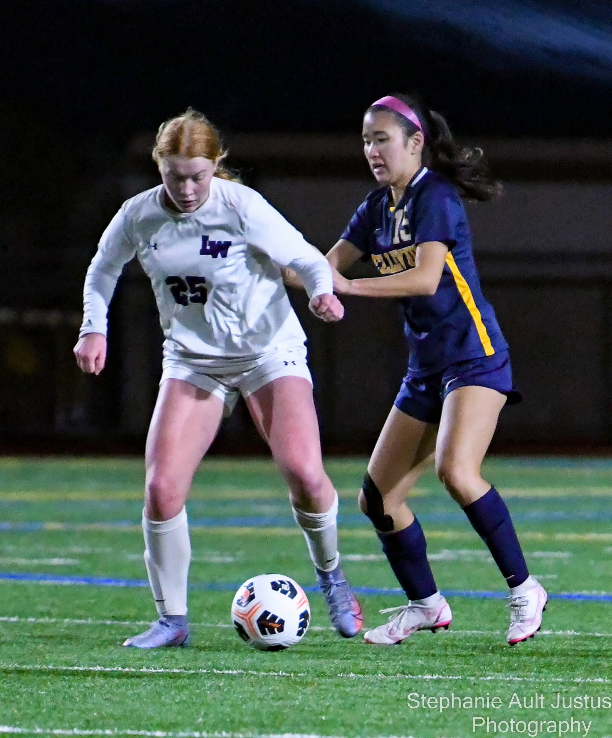 Lake Washington high freshman keeps their eyes on the ball as Bellevue senior Arin Oh (#15) attempts to steal it. Courtesy of Stephanie Ault Justus.