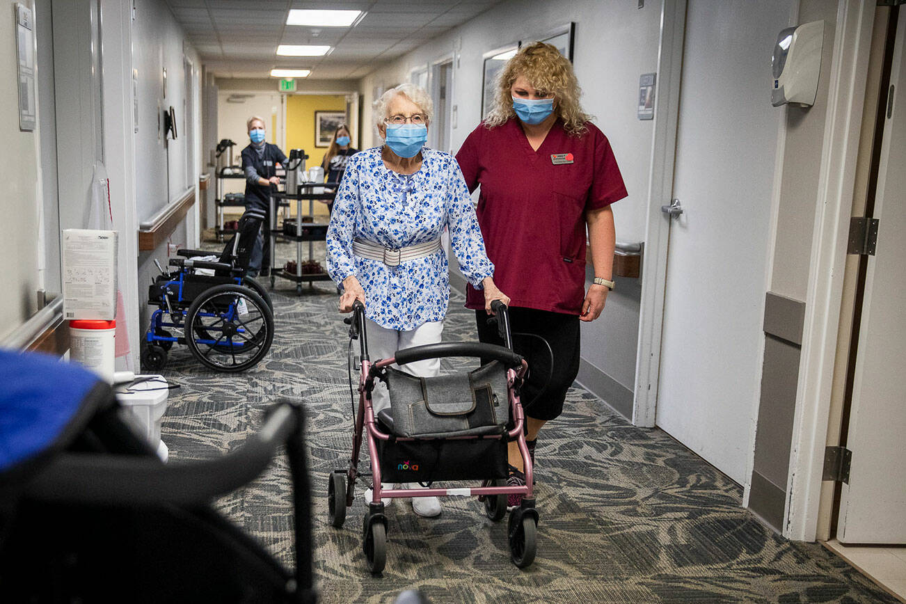 CNA Nina Prigodich, right, goes through restorative exercises with long term care patient Betty Long, 86, at View Ridge Care Center on Friday, Feb. 10, 2023 in Everett, Washington. (Olivia Vanni / The Herald)