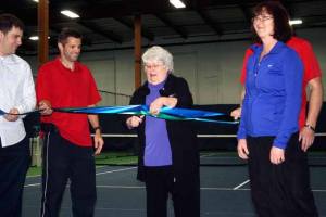 Kirkland Deputy Mayor Doreen Marchione (center) cuts the ribbon during a grand opening celebration at the Outreach and Performance Tennis Center in Kirkland on Friday. Also pictured is Travis Roach