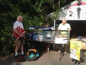Larry Long and Dave Farrell prepare merchandise for the parking lot sale to benefit Hopelik on Aug. 29.