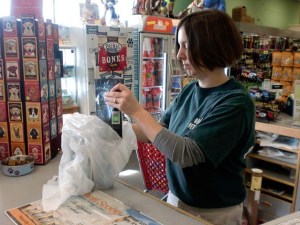 Denny’s Pet World manager Kelly Parsons bags a customer’s purchase using a plastic bag