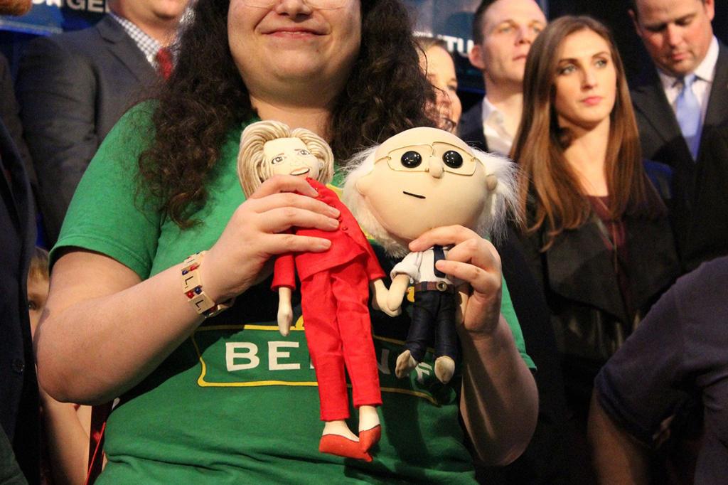 A member of the crowd at the Washington State Democrats election party holds dolls of Hillary Clinton and Bernie Sanders (Allison DeAngelis/staff photo).