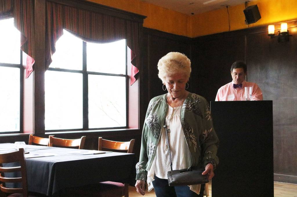 Connie Hogue draws attention to the purse as emcee J.D. Drollinger describes her outfit. CATHERINE KRUMMEY/Kirkland Reporter