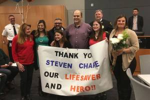 On April 17, Doug Rough (center, in purple shirt) went into cardiac arrest while exercising at the 24 Hour Fitness in Bothell. Steven Charie (to Rough&rsquo;s left, in glasses) performed CPR on Rough and saved his life. They are pictured with members of Rough&rsquo;s family after the City of Kirkland honored Charie. Courtesy of the City of Kirkland