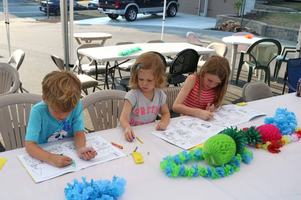 From left to right: Calvin Pohlman, 5, and sisters Emerson, 2, and Payton, 7, color during a community barbecue on National Night Out in Kirkland Tuesday. Megan Campbell/staff photo